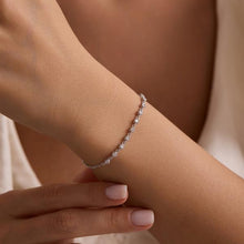 Silver bracelet on a wrist with a neutral background