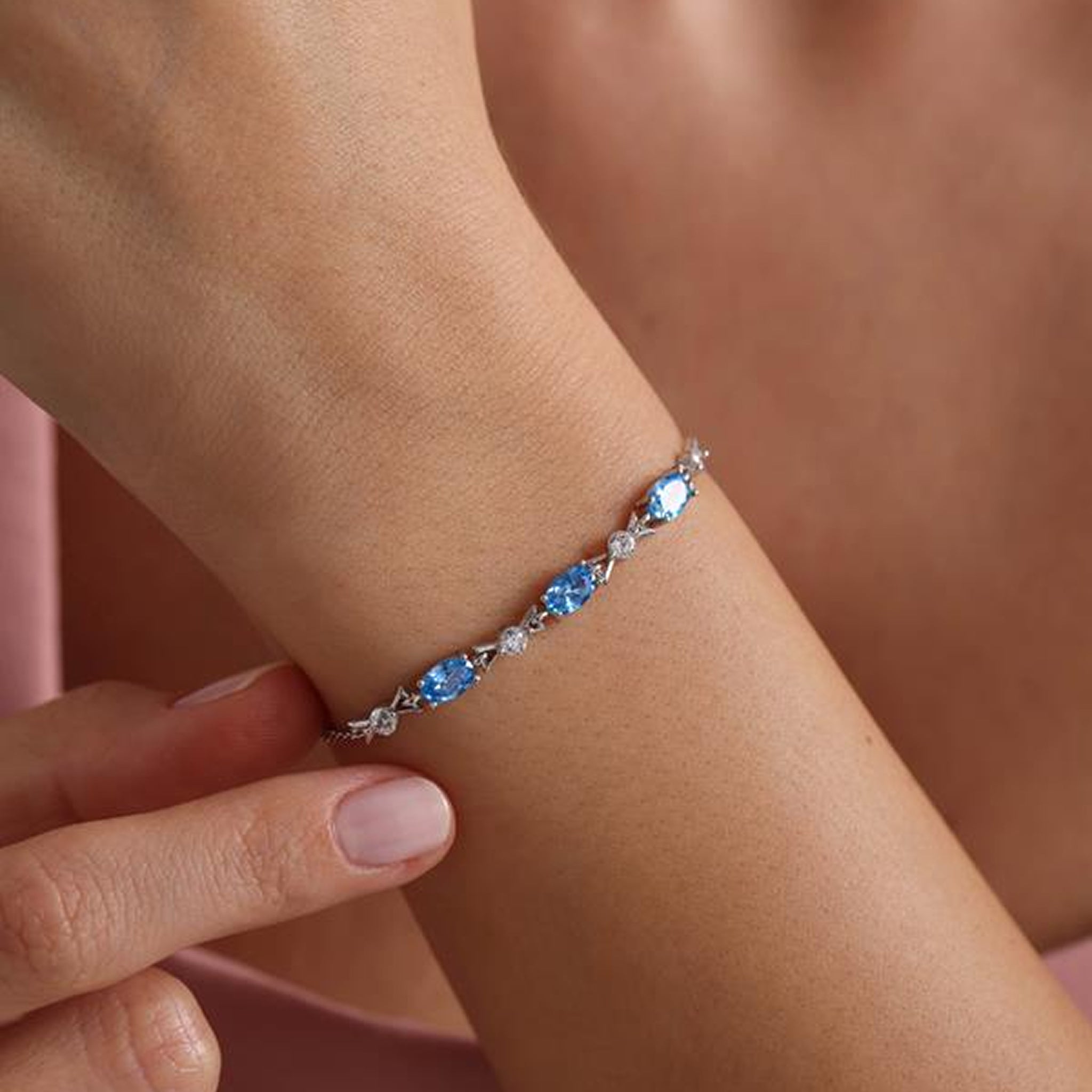 Bracelet with blue stones on a wrist against a neutral background