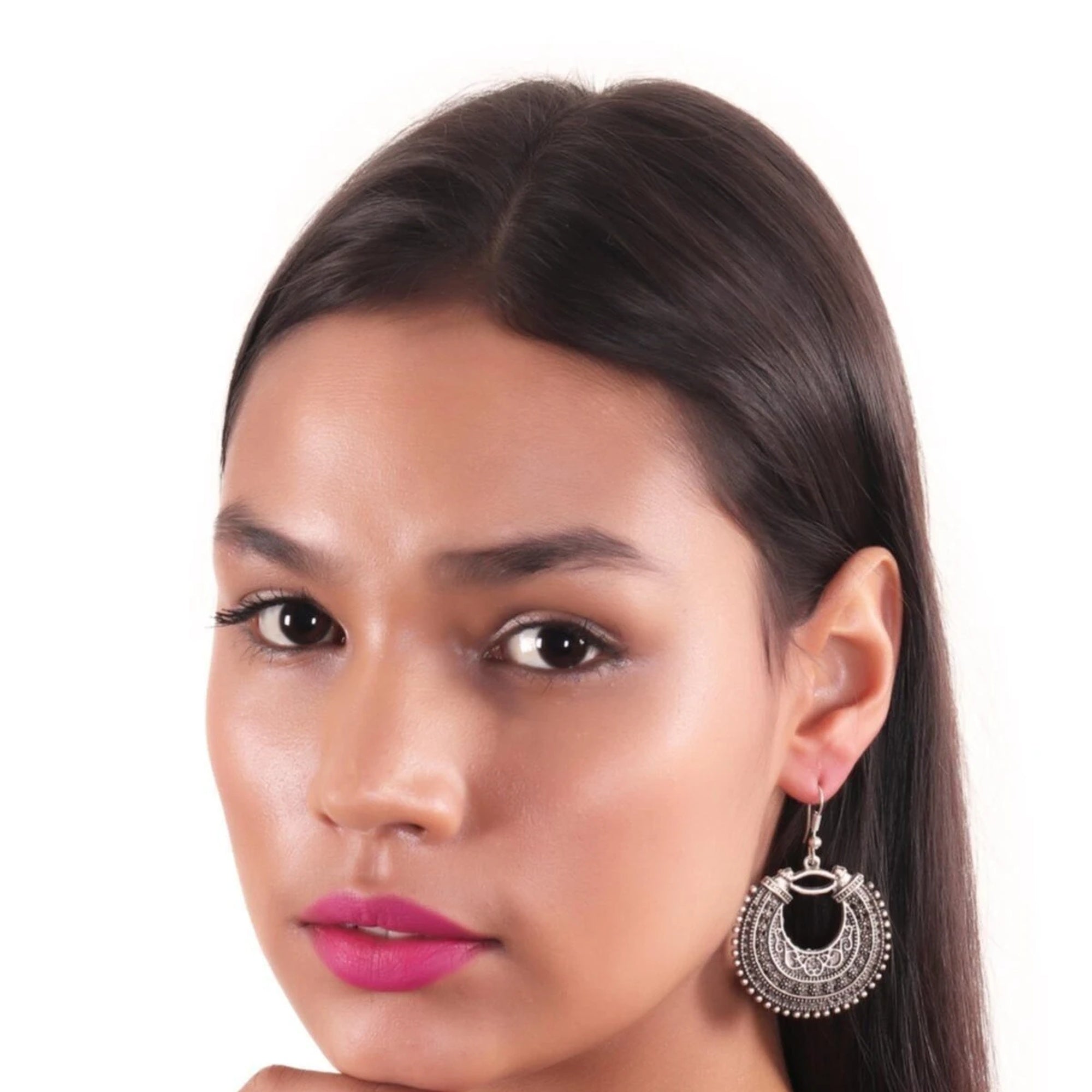 Close-up of a woman wearing silver hoop earrings with a white background