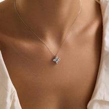 Silver necklace with a floral pendant on a model wearing a white blouse.
