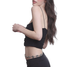 Woman wearing a black top and black pants with a silver belt on a white background