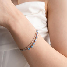 Close-up of a person's arm wearing multiple bracelets with blue beads on a white background