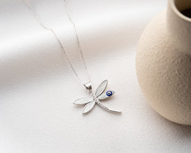 Model wearing symbolic dragonfly necklace with Evil Eye