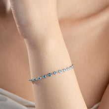 Silver bracelet with blue stones on a person's wrist against a neutral background