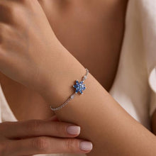 Silver bracelet with a blue flower-shaped gemstone on a wrist.