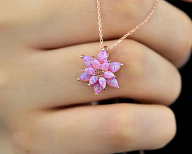 Close-up of a radiant pink fire opal necklace with a handcrafted lotus flower pendant in sterling silver.