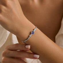 Silver bracelet with a purple gemstone on a wrist against a neutral background