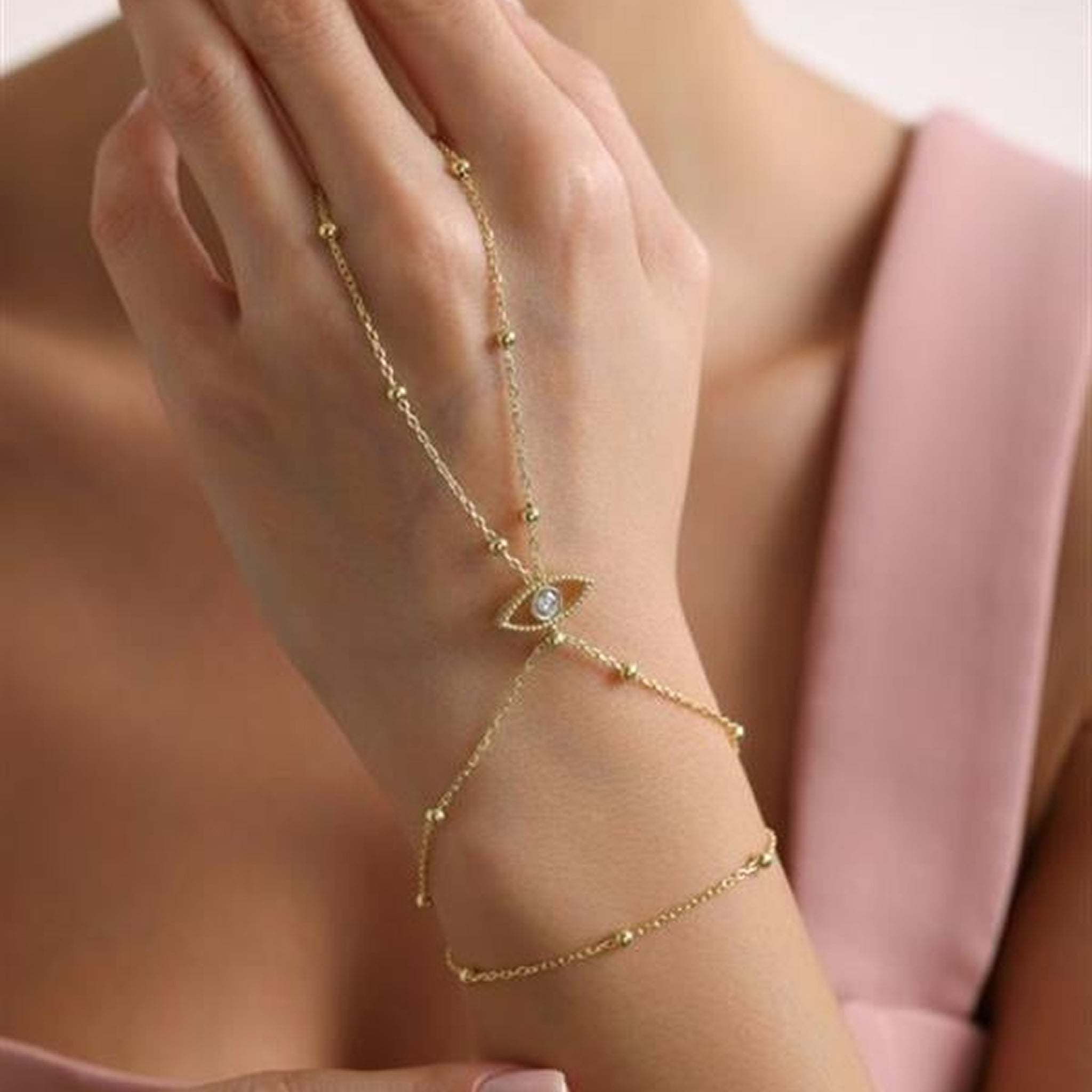 Gold bracelet with a diamond on a hand against a neutral background