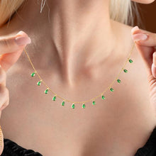 Gold necklace with green gemstones being worn by a person