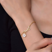 Gold bracelet with floral design on a wrist against a black background