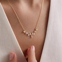 Gold necklace with small diamonds on a person wearing a white outfit