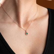 Rose gold necklace with a green gemstone pendant on a person wearing a black top.