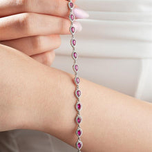 Bracelet with pink gemstones on a wrist against a neutral background