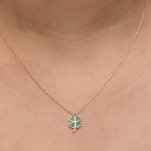 Necklace with a green four-leaf clover pendant on a person's neck.