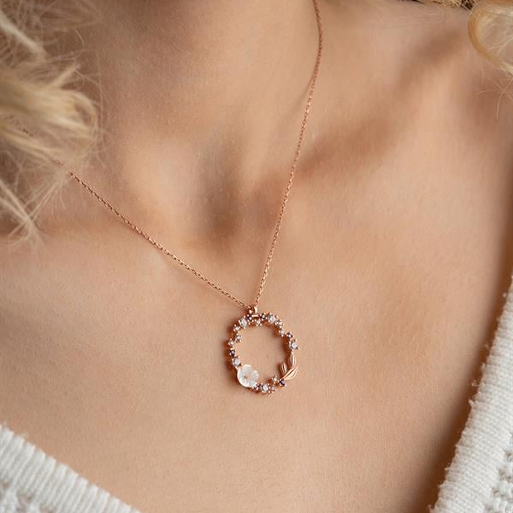 Necklace with a floral pendant on a person wearing a white top