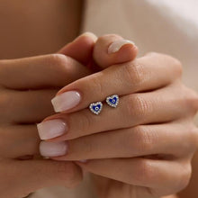 Heart-shaped earrings with blue and white details on a hand