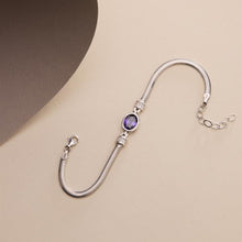 Silver bracelet with a purple gemstone on a beige background