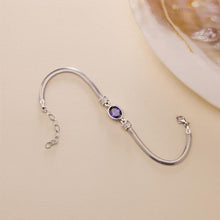 Silver bracelet with a purple gemstone on a beige background