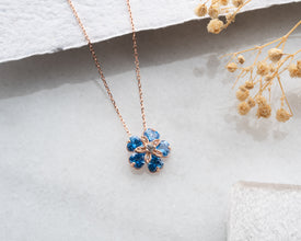 Sterling silver necklace with flower charm resting on stand