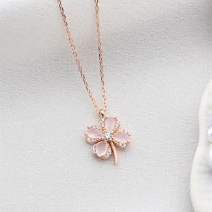 Rose gold necklace with a clover-shaped pendant on a light gray background