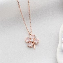 Rose gold necklace with a clover-shaped pendant on a light gray background