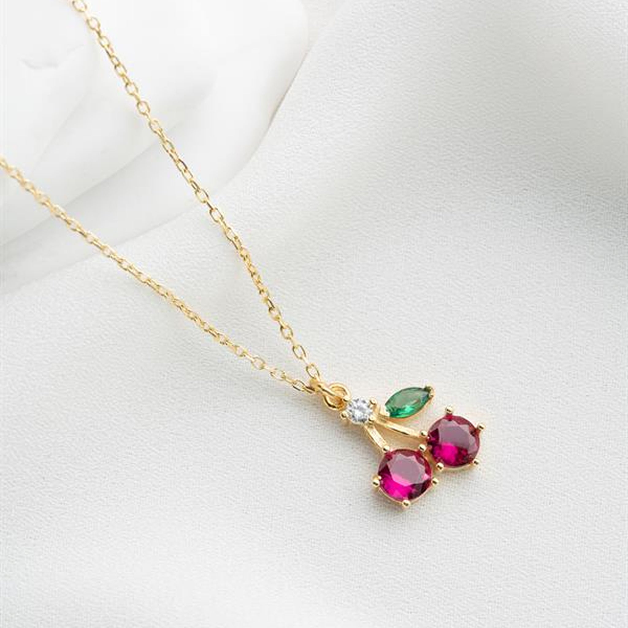 Gold necklace with three gemstones on a white background
