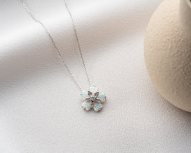 Close-up of a detailed floral pendant necklace featuring an opal gemstone with natural iridescence.