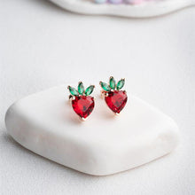 Heart-shaped earrings with red and green stones on a white surface