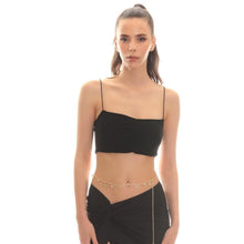 Woman wearing a black top and skirt with a gold chain detail on a white background