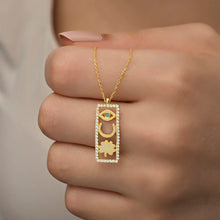 Gold necklace with a rectangular pendant featuring an eye design held by a hand.
