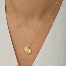 Gold necklace with a heart-shaped pendant on a neutral background