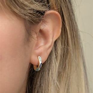 Close-up of an ear wearing a silver earring with a small gemstone.