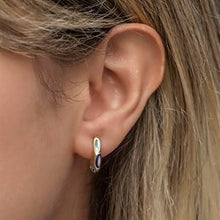 Close-up of an ear wearing a small hoop earring with a blurred background