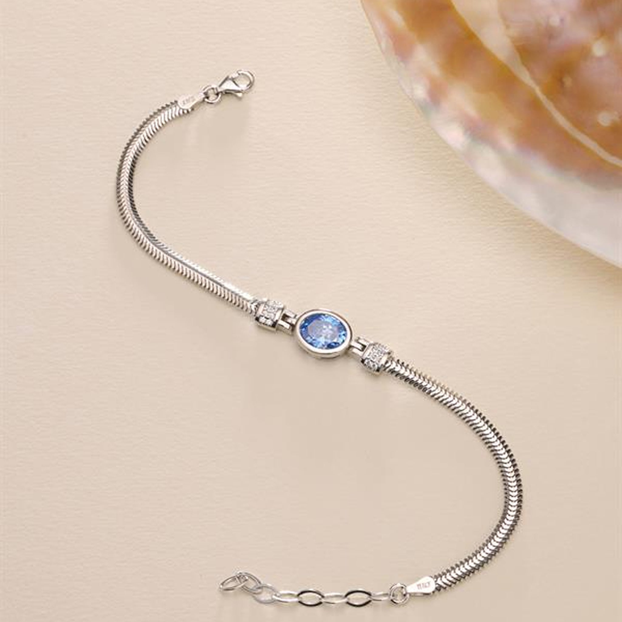 Silver bracelet with a blue gemstone on a beige background