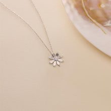 Silver flower-shaped necklace on a beige surface