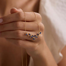 Close-up of gold-plated 925 sterling silver ivy vine pendant necklace with blue marquise zircon stones on white background.