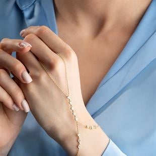 Close-up of a person wearing a gold bracelet with a soft focus background