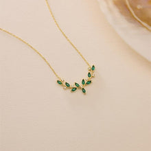 Gold necklace with green gemstones on a beige background