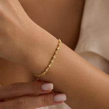 Gold bracelet on a wrist with a neutral background