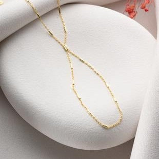 Gold necklace on a white stone surface