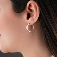 Close-up of a person wearing a gold hoop earring.