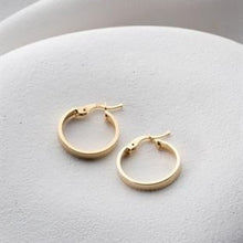 Gold hoop earrings on a light gray surface