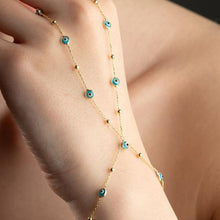 Gold anklet with blue eye charms on a person's ankle against a neutral background