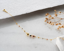 Stacked mixed metal bracelets showing gold, silver and rose gold beads on marble