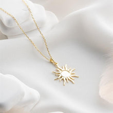Gold sun-shaped pendant necklace on a white surface