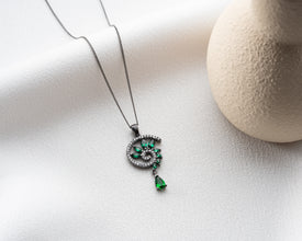 Gothic emerald spiral pendant glowing against black velvet