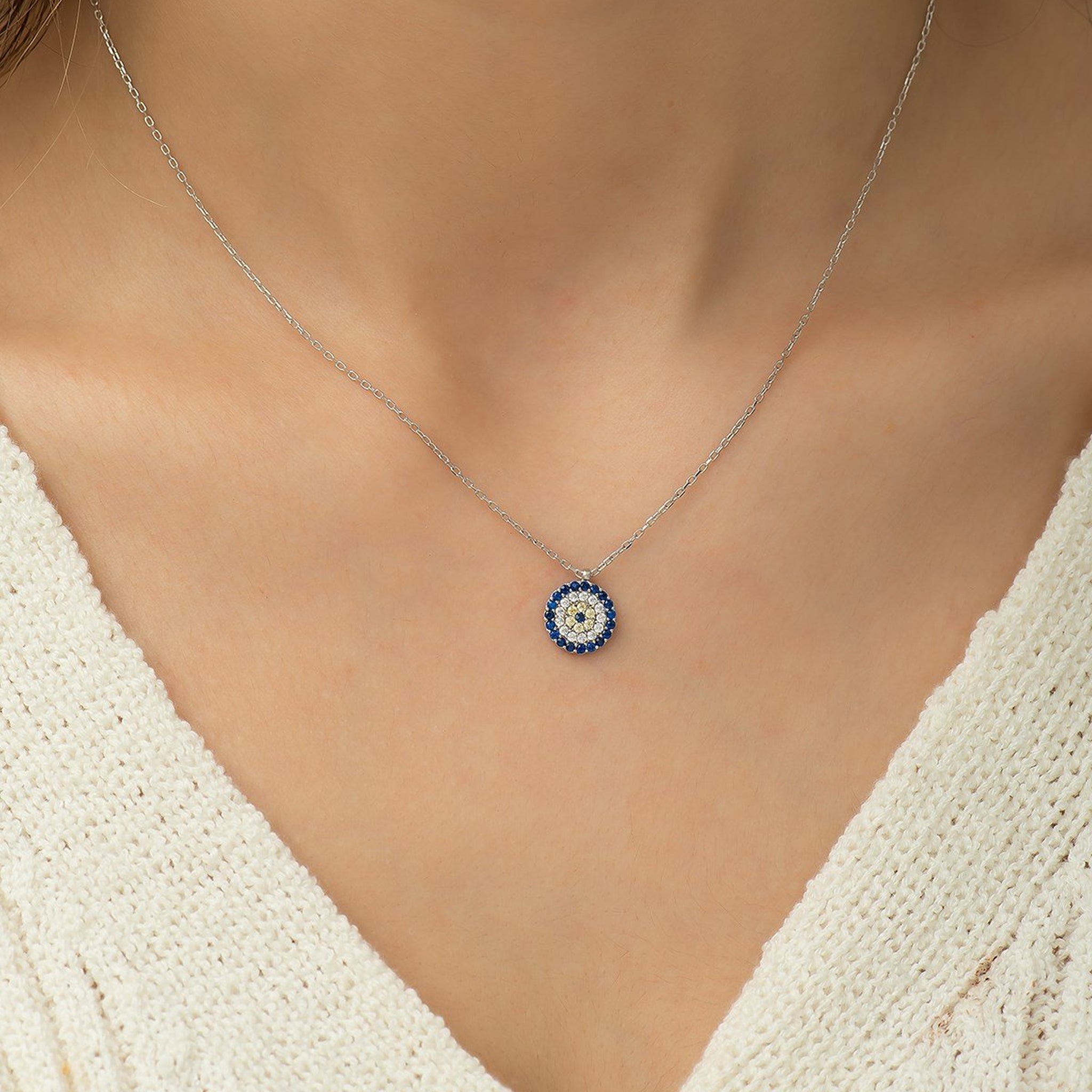 Necklace with a blue and white pendant on a person wearing a white top.