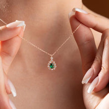 Rose gold necklace with an emerald pendant held by a person