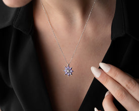 Handcrafted sterling silver floral pendant with a sparkling purple gemstone.