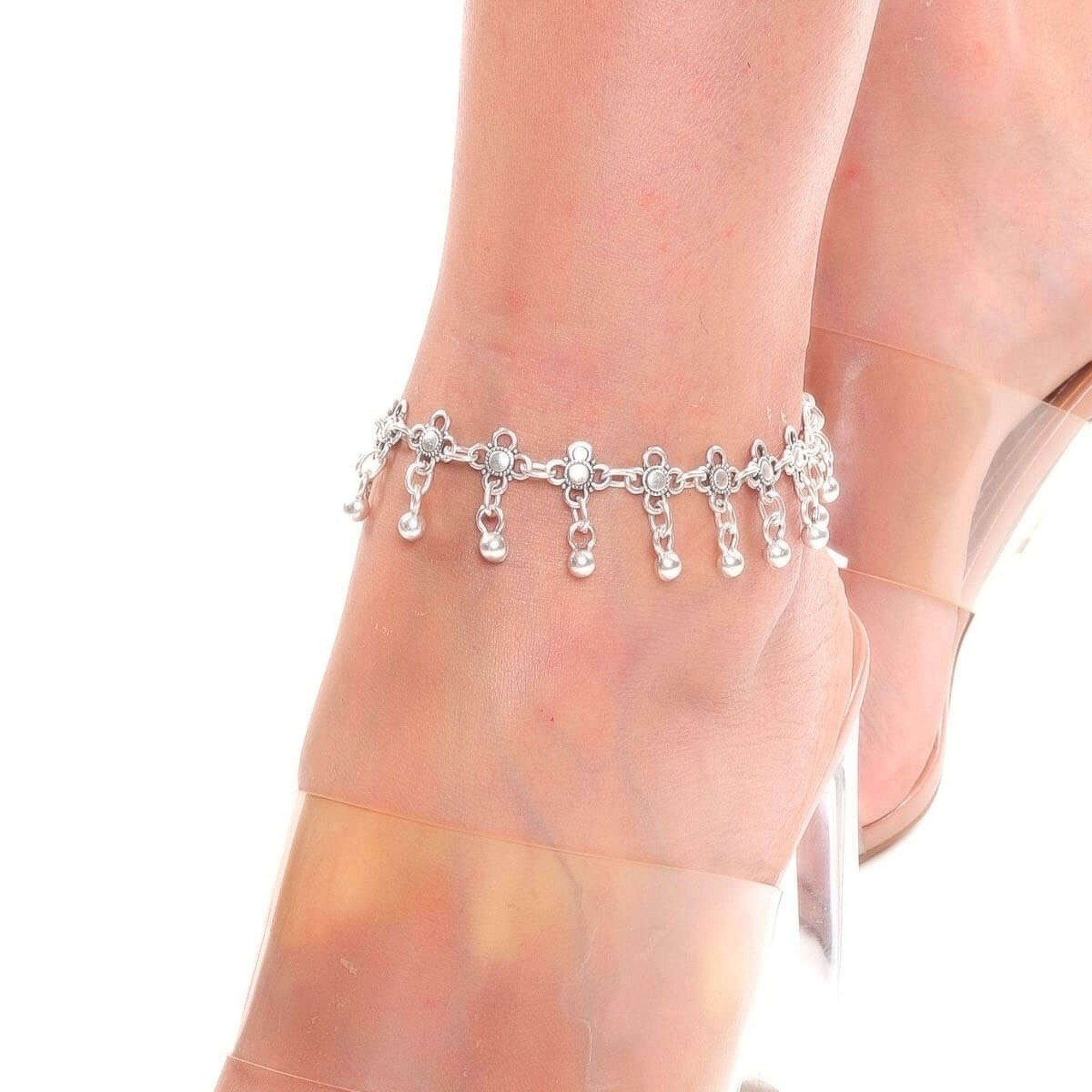 Silver anklet on a person's ankle with sheer white stockings.
